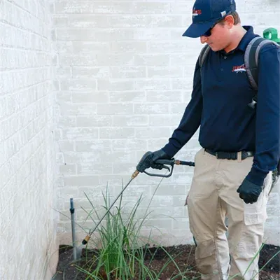 tech spraying exterior of home