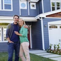 man and woman standing in front of a blue house